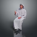 Man Sitting And Smiling In White Traditional Clothing With Headscarf Gesturing Against Gray Background