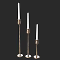 Three Brass Candle Lamps With Slender Stands And White Candles For Home Decor
