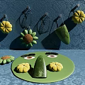 Colorful Flower Decorations Hanging On Blue Patterened Wall With Green Plate Items On Table