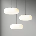 Three White Oval Pendant Lights With Paper Shades Hanging On Gray Wall