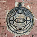 Traditional Manhole Cover On Red Brick Pavement With Intricate Circular Design