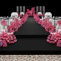 Elegant Banquet Hall Featuring Pink Floral Arrangements Black Stage White Tables Chandeliers And Patterned Carpet
