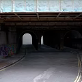 Modern Urban Underpass With Arched Tunnels Graffiti Covered Brick Walls And Paved Road