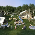 Lush Green Camping Site with Tents String Lights and Outdoor Seating for Activities