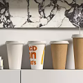 Branded White and Brown Paper Cups with CPN D's on White Shelf against Marble Wall