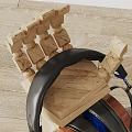 Wooden Stand Holding Black Headphones and Blue Speaker with Cables on Wooden Floor White Wall