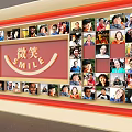Collage of People's Smile Photos on Display Wall with Smile Sign