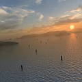 Stunning Sunset Lake Landscape With Distant Misty Mountains And Golden Sunlight Shining On Calm Water