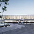 Modern Building Exterior With Glass Curtain Wall Paved Square Art Sculpture Water Feature And Trees