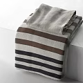 Folded Striped Towel With Gray Brown Black Stripes On White Surface