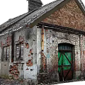 Old Industrial Factory Building with Weathered Roof Red Brick Plaster Walls Peeling Sections and Green Door