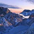 Breathtaking Garden Landscape With Snow Covered Mountains Rocky Terrain Calm Lake And Sunset Sky