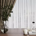 Green Plant in Glass Vase on Wooden Table with Curtain Indoor and White Balls Glassware
