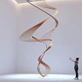 Spiral Wooden Art Installation in Bright White Room With Skylight and Person Standing Beside