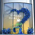 Heart Shaped Blue Floral Display In Front Of Glass Window With Green Chair And Bouquets
