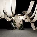 Stylish Floral Display Featuring White Draped Fabric And Central Decorative Greenery On Gray Floor