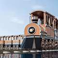 Vintage Steam Train With Orange Brown Carriages Large Wheels And Water Reflection Under Blue Sky