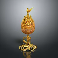 Golden egg shaped decorative ornament set with bird on top and intricate base design