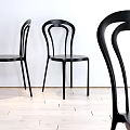 Black Curved Back Leisure Chairs In Minimalist Setting With White Wall And Light Wooden Floor