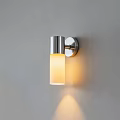 Modern Stainless Steel Wall Light With Frosted Glass Shade And Warm Illumination On Gray Wall