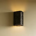 Dark Colored Square Wall Lamp With Textured Surface Mounted On Wall Illuminating Warm Light