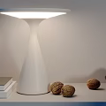 Modern White Table Lamp Glowing on Table with Books Walnuts and Bowl of Pears