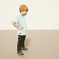 Red Haired Boy in Light Blue T-Shirt Posing with Hands on Hips Against Light Background