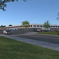 Modern Industrial Factory Exterior With Spacious Road And Delivery Trucks Near Green Trees