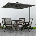 Outdoor Table With Chairs and Umbrella in Gravel Area Decorated With Green Plants