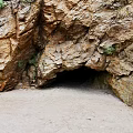 Natural Stone And Wood Cave Entrance Featuring Rocky Formation And Greenery