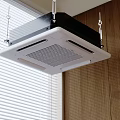 Modern Ceiling Mounted Air Conditioner Fan In Indoor Room With Wooden Wall And Window Blinds