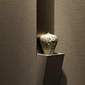 Ceramic Vessel With Intricate Patterns Showcased In Wall Niche Against Gray Textured Wall