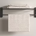 Patterned Light Colored Towel Hanging On Black Towel Rack With Folded Towels On Top