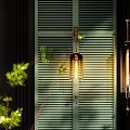 Warm Light Wall Lamps Mounted On Dark Background With Green Plants And Louvered Shutters