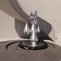 Modern Landscape Sculpture Featuring Silver Droplet Shapes on Black Base with Gray Curved Wall Background