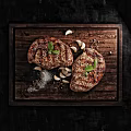 Grilled Steak on Wooden Cutting Board with Garlic Cloves Black Peppercorns Salt and Basil Leaves