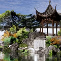 Traditional Chinese Garden Pavilion Featuring Rockery Waterfall Pond and Lush Greenery by White Wall
