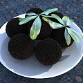 Fresh Black Fruits Arranged On White Plate With Green Leaves On Dark Patterned Tablecloth