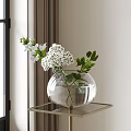 Transparent Glass Vase With White Flowers And Green Leaves On Gold Metal Table Near Window
