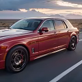 Red Rolls-Royce Sedan Driving On Open Highway With Mountain Sunset View