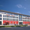 Modern Fire Station Building Exterior With Red Doors Fire Engines And Emblem Under Blue Sky
