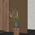 Dark Blue Vase With White Small Flowers And Green Branches On Wooden Round Stand Light Wall Background