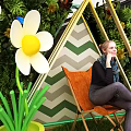 Mall Decorative Display Area With Green Plant Wall Triangular Frame White Flowers And Chair