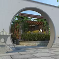Traditional Garden Landscape With Circular Archway Wooden Pergola Green Plants Yellow Flowers And Stone Lanterns