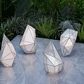 Geometric Design Outdoor Lights With White Finish On Gray Tabletop And Green Plants