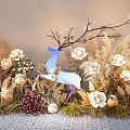 Vibrant Flowers And Dried Grass With Blue Deer Decoration Against Gray Wall On Pebble Ground