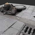 Landscape Sculpture of Man in Hard Hat Reclining on Paved Ground Near Sewer Cover