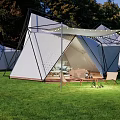 Modern Geometric Outdoor Tent In Grass Field With String Lights And Wooden Furniture