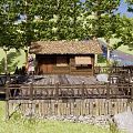 Rustic Lodge With Thatched Roof Wooden Platform And Outdoor Rest Area Surrounded By Green Trees