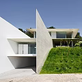 Modern Detached Villa Featuring White Exterior Sloped Geometric Structure And Green Lawn